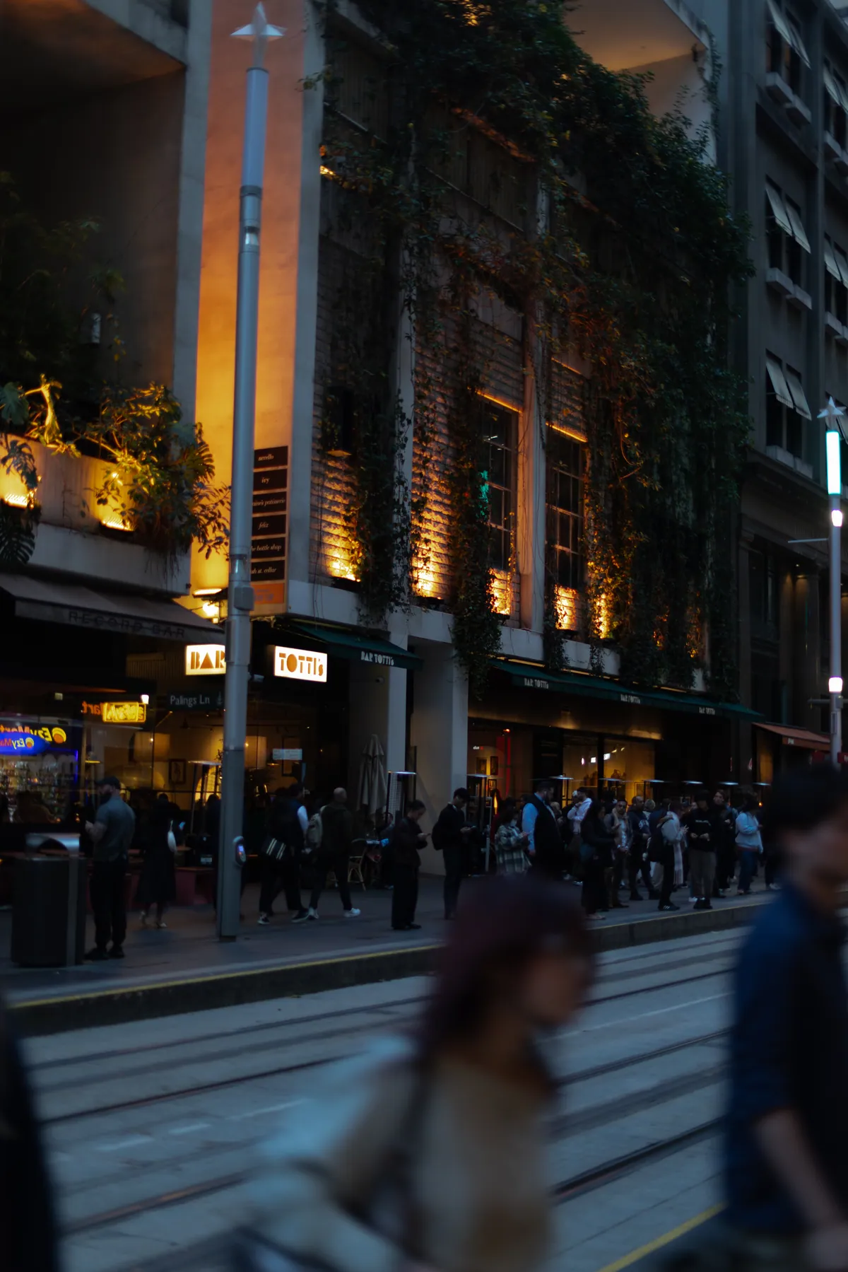 Pedestrians blurring past lit storefronts on a busy evening street