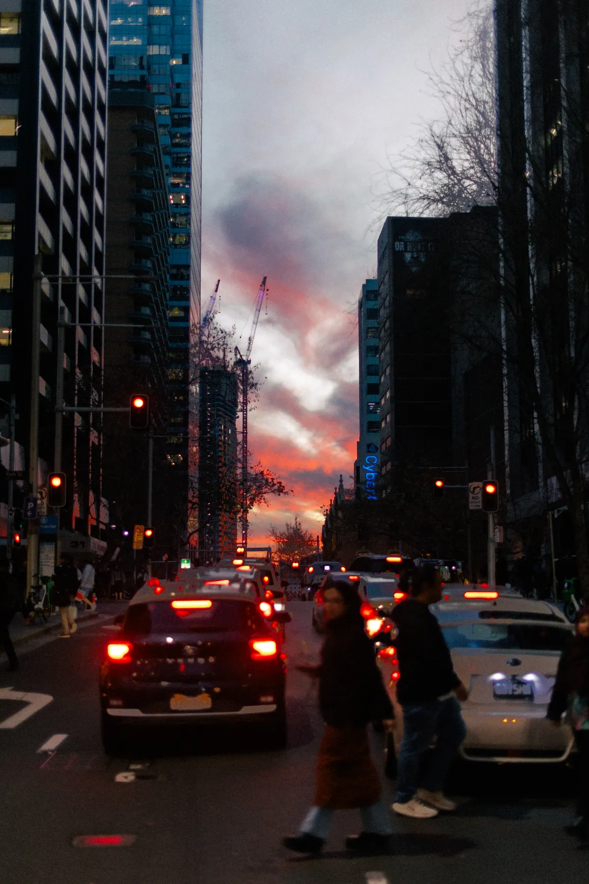 George Street traffic and pedestrians at dusk under a pink sunset between city towers