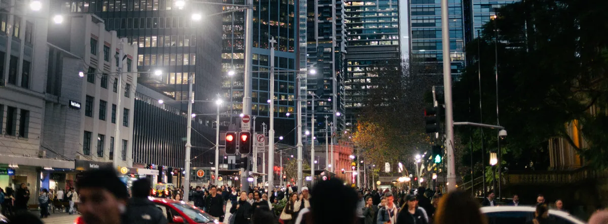 Wide night view of a crowded city street under rows of streetlights and lit office towers