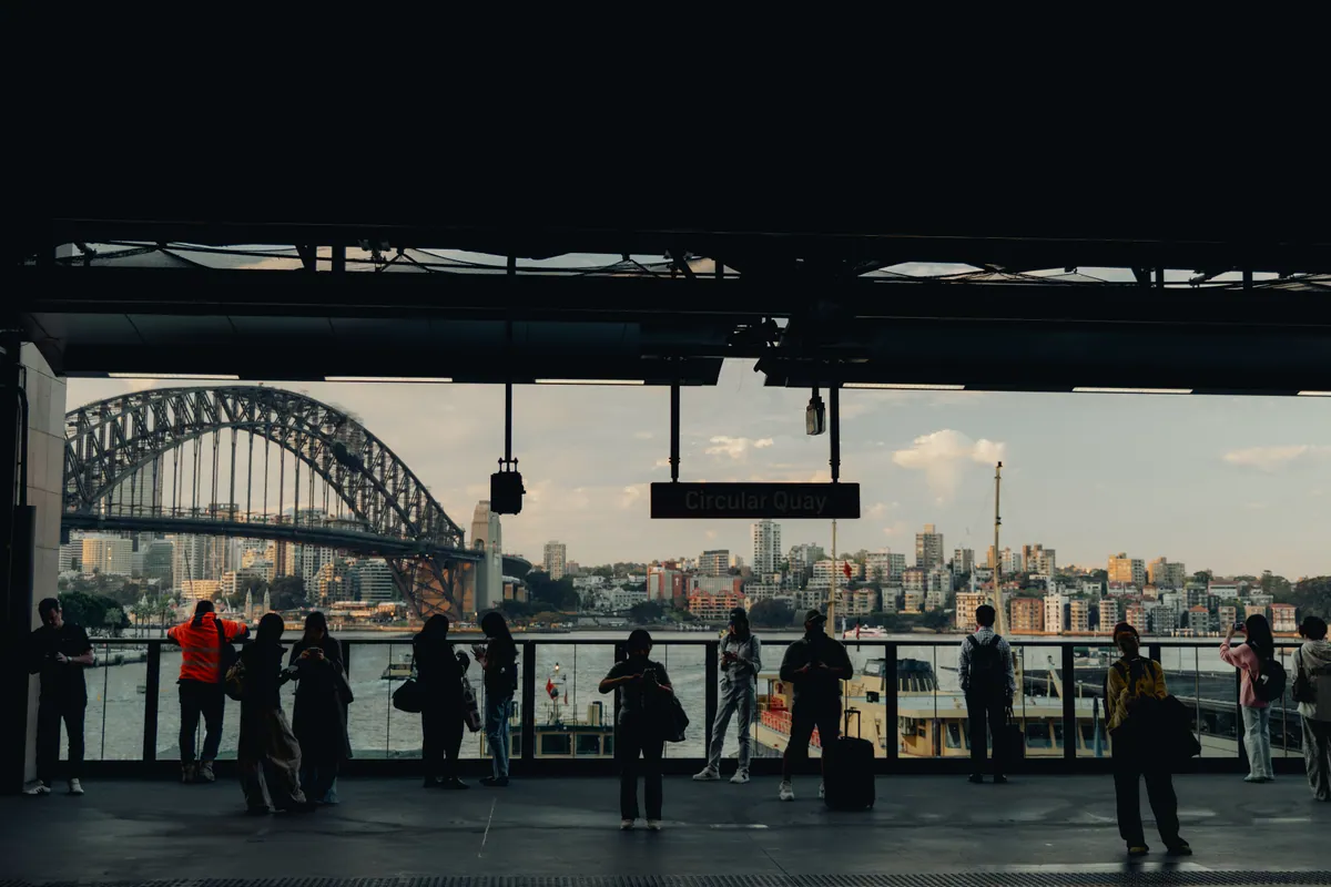 Commuters in silhouette on the Circular Quay platform, the bridge framed beyond